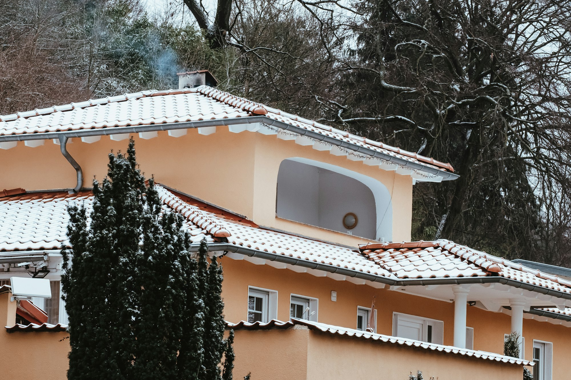 Big private house covered by snow in winter and smoke coming out of the chimney