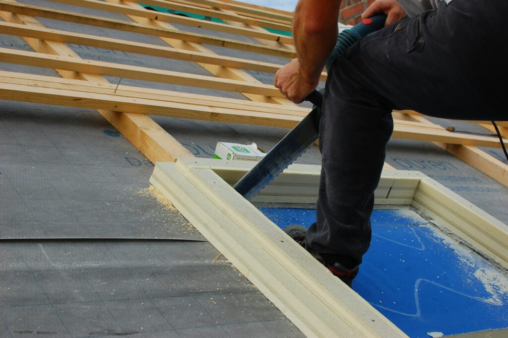 Builder cutting a hole for skylight in roof insulation material