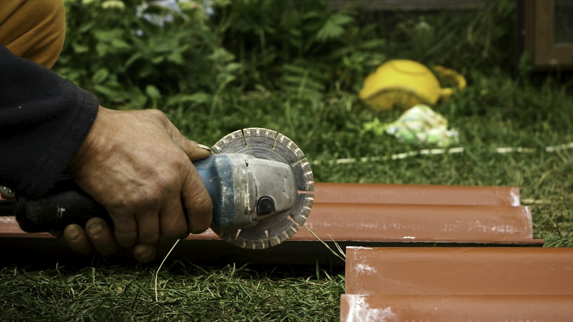 Roofer using an angle grinder machine to cut a roof tile of red color. Stock footage. Close up of